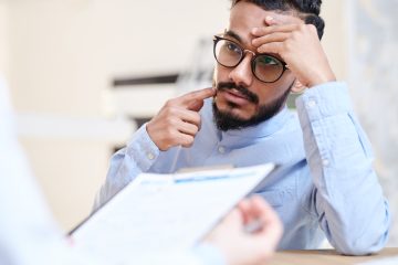 concerned looking man holds finger to jaw